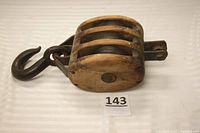 Side view of the triple pulley block with hook showing wood frame and steel sheaves