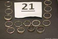 Photo showing all 15 sterling silver rings arranged on a black cloth background with identification card showing '21'.