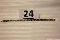 Full length view of the bracelet laid out flat showing the alternating dark blue stones and silver 'X' shaped links.