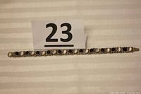 Full length top view of the vintage sterling silver bracelet with black and white stones on beige fabric