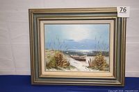 Framed shore scene oil painting showing boat on sandy path through grassy dunes with ocean and birds. Front view showing overall artwork and frame condition.