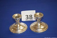 Front and side view of pair of sterling silver weighted candle holders with round base and decorative edge.