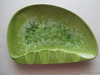 Top view of the green ceramic dish with mottled acid drip glaze design and ridge for holding cigars or cigarettes.