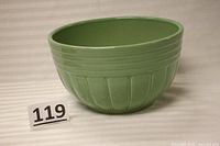 Front and side view of the green ceramic mixing bowl, showing exterior panel design and overall shape.