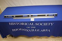 Full view of the 48-inch Sears ribbed I-beam level and the 36-inch aluminum Fairgate ruler on display blue tablecloth background.