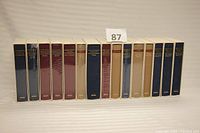 Wide view of 15 Library of America books upright in protective sleeves, colors blue, maroon, beige