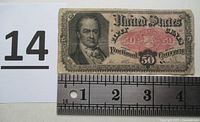 Front view of U.S. shinplaster 50 cent paper currency showing portrait and denomination with ruler for scale