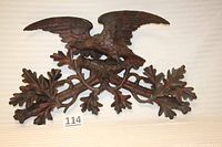 Full front view of the wooden carved eagle wall display showing entire carving across with branches and leaves spread below the eagle with detailed wings outstretched.