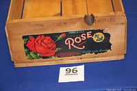 Front view of the wooden crate showing colorful "Rose Brand" label with red rose illustration and text "California Fruits".