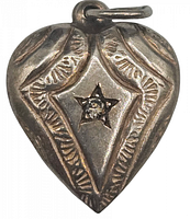 Front of antique sterling silver heart-shaped charm showing engraved pattern and clear stone set in star-shaped bezel.