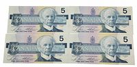Front of four Canadian five dollar bills showing the portrait of Sir Wilfrid Laurier, dated 1986.