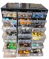 Full frontal photo showing the black organizer chest with 24 partially open drawers filled with various vintage clip-on earrings in assorted colors and sizes.