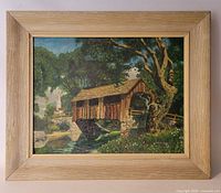 Front view of the framed oil painting depicting a covered wooden bridge and landscape scene.