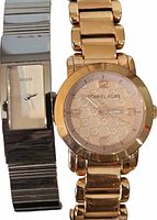 Photo showing gold-tone Michael Kors watch and silver-tone Guess watch side by side