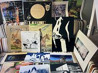 Full view of the collection showing multiple prints, posters, and paintings arranged on a striped sofa.