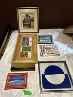 Overview of assorted framed and unframed artwork laid out on white cloth background