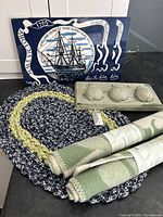 Overview of all items: nautical placemats, oval rag rug, ceramic pear artwork tray with three pears, two rolled woollen mats in green and white check pattern.