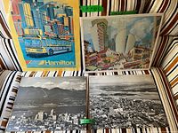 Colorful posters of Hamilton and Toronto and vintage black and white photographic boards of Montreal and Vancouver shown on a striped couch.