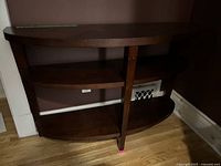 Side view of dark brown half moon console table showing three curved shelves and vertical support.
