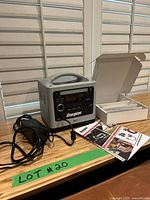 Energizer Arc3 portable power station shown with power adapter, multiple cables, user manual, and the original box on wooden table.