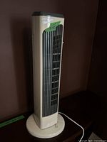 Full view of the beige and gray Fellini tower fan showing front vertical grille and round base.