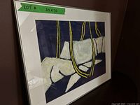Framed abstract painting showing blue, white, and yellow colors, angled side view, including green label indicating 24x30 size.
