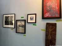 Five framed artworks displayed on a wall with green size tags