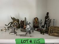 Wide shelf view of all figurines showing variety of historical and mythical themes including Pharaoh bust, lions, winged lion, obelisk, and miniature windmill.