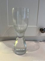 Single clear glass showing thick rounded base, tapered body, and wider top edge.