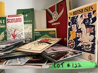 Shelf with assorted vintage maps and travel guides, showing titles and covers including Scotland, British Isles, Chicago and Berlin Olympics map.