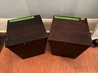 Two closed wooden storage boxes side by side on carpet, showing dark brown finish and top surfaces with some scratches.