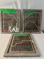 Set of 3 framed artworks showing city maps of Tokyo, Paris, and London, each with a green sticker indicating lot and size information.