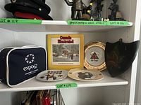 Shelved display showing navy Expo 67 bag, Canada Illustrated book, decorated plates and decorative shield