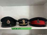 Photo showing three vintage hats side by side on a white shelf. Each has a distinct emblem and color scheme.