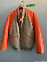 Front view of the Y-3 bomber jacket showing tan wool body and bright orange leather sleeves with zippered front and pockets.