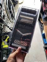 Top angled photo of a rectangular mandoline slicer with black and clear plastic body, showing the multiple stainless steel blades for slicing and julienne cuts.