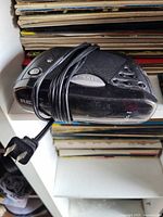 Black Ricoh alarm clock radio with power cord wrapped around it, viewing from the top and side showing control buttons and AM/FM switch.