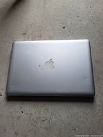 Closed Apple MacBook Pro showing silver aluminum top case with minor dent and Apple logo