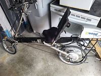 Recumbent e-bike folded out, left side view showing frame, seat, handlebars, motor and battery