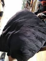 Black throw blanket shown draped over a surface, displaying soft texture and slight horizontal lines.