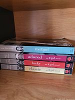 Four paperback novels stacked horizontally, showing colorful spines with author name Cecily von Ziegesar and titles: The It Girl, Adored, Lucky, Classic.