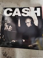Front cover of Johnny Cash vinyl record showing a black and white image of Johnny Cash in a recording session with CASH in bold letters at the top.