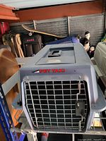 Side angled view showing gray plastic body and metal wire door of Pet Taxi carrier.