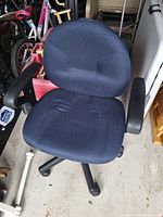 Photo showing a black fabric computer chair with padded armrests and adjustable height base.