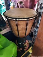 Photo of a wooden djembe drum with natural skin top and painted black base featuring tiger and wolf designs.