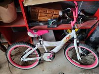 Full side view of the white and pink kids bike with princess-themed decorations and visible training wheels.