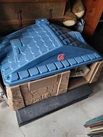 Blue roof with textured tiles and tan walls resembling stone with green door on front.