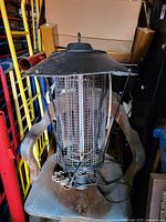 Large bug zapper placed on a chair, showing metal grid and protective cover, power cord trailing on the chair seat.