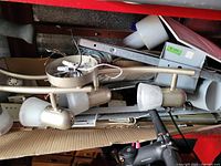 Photo showing a 4-bulb track light with matte gold finish and frosted glass shades, laid on top of a cardboard box with other metallic parts.