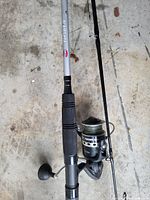 Close-up of Penn Pursuit IV fishing rod and spinning reel with braided line laid on concrete floor.